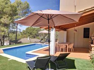 a patio with an umbrella next to a swimming pool at Villa Barcelona en Olivella in Olivella