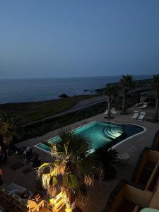 una piscina con palmeras y el océano en Hotel Bue Marino en Pantelleria