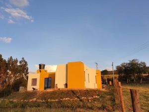 une maison jaune et blanche au-dessus d'un champ dans l'établissement Mirador Casa Blanca Campestre, à Tibasosa