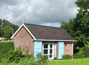 a small brick building with blue doors on a field at Tolhuisje bij Driezum in Driesum