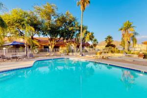 a large blue swimming pool with chairs and palm trees at Tucson National #8689 in Tucson