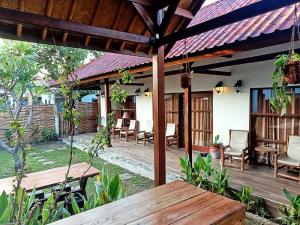 un patio al aire libre con mesa de madera y sillas en Classico Italiano, en Gili Air