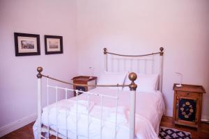 a bedroom with a white bed and a wooden night stand at Oasis in Nieu-Bethesda