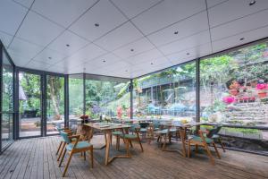 ein Esszimmer mit Tischen, Stühlen und großen Fenstern in der Unterkunft Garden Villa Resort Yangshuo in Yangshuo