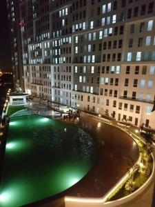 a large green pool in a city at night at Apartemen Comfy Urbano Bekasi in Bulanbulan