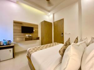 een witte slaapkamer met een bed en een televisie bij Arogyadham Retreat in Rishīkesh