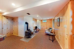 a living room with wood paneling and a stove at Tumblehome Cabin in Rangeley