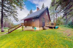 a large wooden house with a porch on a yard at Tumblehome Cabin in Rangeley