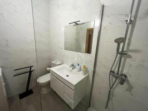 ein weißes Bad mit einem Waschbecken und einer Dusche in der Unterkunft Casa do Pastor in Carragozela