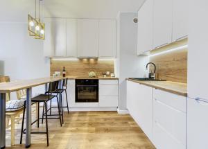 a kitchen with white cabinets and a wooden counter top at Sea and City Apartments with Balcony by Rentujemy in Gdańsk