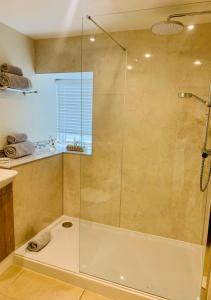 a shower with a glass door in a bathroom at The Beautiful Bobbin - Premium Place to stay - Cottage with views, local walks & pubs in Tideswell