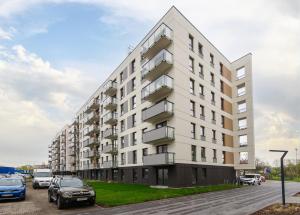 a large white building with cars parked in a parking lot at Sea and City Apartments with Balcony by Rentujemy in Gdańsk