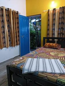 1 dormitorio con 2 camas y puerta azul en Peace and love stay en Alleppey