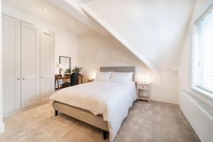 a white bedroom with a bed and a window at 2 The Quadrant Luxury Apartments - Hoylake in Hoylake