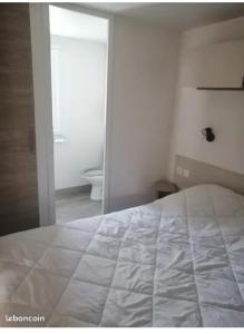 a bedroom with a white bed and a mirror at sweet mobil-home in Lège-Cap-Ferret