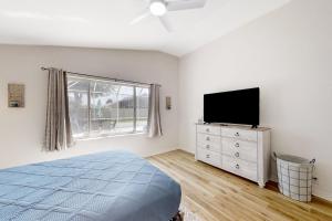 1 dormitorio con 1 cama y TV de pantalla plana en The Barefoot Bungalow, en Palm Coast