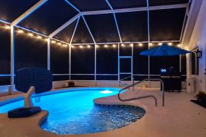 ein großer Swimmingpool mit Sonnenschirm und Sonnenschirm in der Unterkunft The Barefoot Bungalow House in Palm Coast with an enclosed pool & grill in Palm Coast