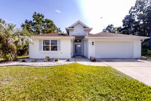 ein weißes Haus mit Garage in der Unterkunft The Barefoot Bungalow House in Palm Coast with an enclosed pool & grill in Palm Coast