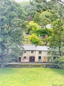 una casa de piedra con puertas naranjas en medio de un campo en The Beautiful Bobbin - Premium Place to stay - Cottage with views, local walks & pubs, en Tideswell