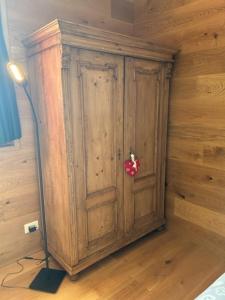 a wooden cabinet in a room with a lamp at Perla Dolomiti Falt in Falcade