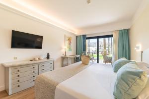 a bedroom with a large bed and a television at CM Mallorca Palace - Only Adults in Sa Coma