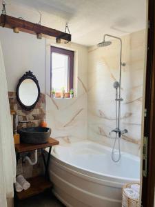 ein Badezimmer mit einer Badewanne, einem Waschbecken und einem Spiegel in der Unterkunft La Casetta - O întreagă căsuță ca în povești in Baia Sprie