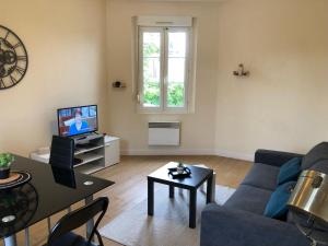 a living room with a blue couch and a tv at La clé de FA - Fibre Wifi - Parking - Calme et tranquilité in Troyes