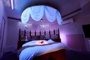 ein Schlafzimmer mit einem Bett in einem lila Zimmer in der Unterkunft ホテル　モモ 