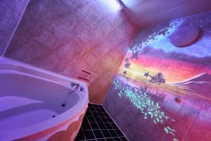 baño con bañera y un arco iris pintado en la pared en ホテル　モモ 