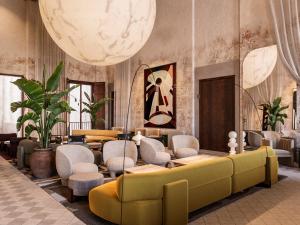 vestíbulo con sofá amarillo y sillas en Nobis Hotel Palma, a Member of Design Hotels, en Palma de Mallorca