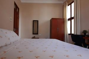 a bedroom with a large white bed with a window at Modern apartment in Stone Town in Stone Town