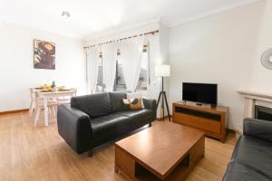 Seaside Deluxe Flat في بينيش: غرفة معيشة مع أريكة جلدية سوداء وطاولة
