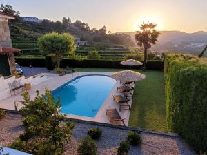 a swimming pool in a garden with umbrellas at Casa de Ladrido in Felgueiras