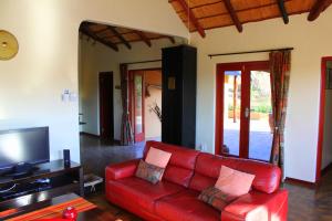 a living room with a red couch and a tv at Bushvilla Umoja Kruger in Phalaborwa