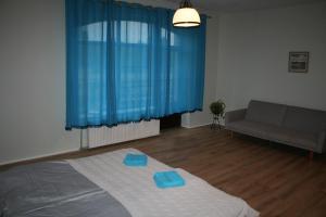 1 dormitorio con cama con sábanas azules y sofá en Brīvdienu māja Tobago, en Plieņciems