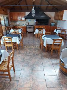 a restaurant with tables and chairs and a kitchen at Hostal Y Cabañas Don Juan in Villarrica