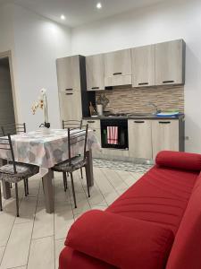 un soggiorno con tavolo e divano rosso di Casa Filomena a Vibo Valentia