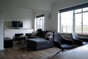 een woonkamer met een bank en 2 stoelen bij Kess Maison, Gehele villa met dakterras Enschede in Enschede