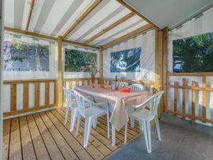 a dining room with a table and white chairs at Camping de Brouël in Ambon