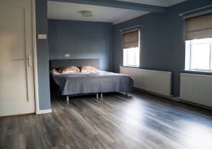 a bedroom with a bed with blue walls and wooden floors at Kess Maison, Gehele villa met SAUNA en dakterras Enschede in Enschede