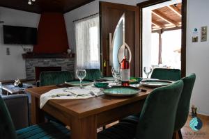 a dining room table with a bottle of wine and green chairs at Villa Foteini in Yerakárion