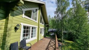 een veranda aan de voorzijde van een geel huis met een terras bij Villa Helmi in Jämsä