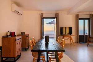 sala de estar con mesa de madera y TV en Luxurious Santorini Escape - Villa Imerovigli - Infinity Pool - Breathtaking Aegean Views, en Vourvoúlos
