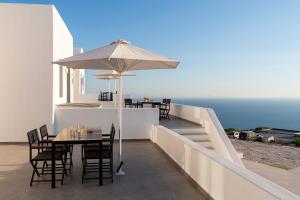 una mesa con sombrilla en un balcón con vistas al océano en Luxurious Santorini Escape - Villa Imerovigli - Infinity Pool - Breathtaking Aegean Views, en Vourvoúlos
