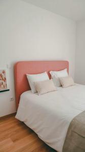 um quarto com uma cama branca e uma cabeceira laranja em Apolo71 Alojamentos em Brangança