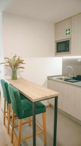 a kitchen with a wooden table and green chairs at Apolo71 Alojamentos in Bragança