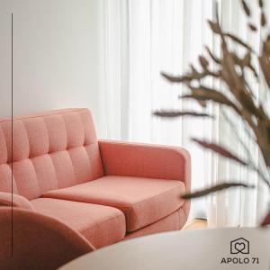 a living room with a pink couch and a plant at Apolo71 Alojamentos in Bragança