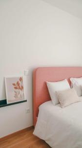 a bed with an orange headboard and white pillows at Apolo71 Alojamentos in Bragança