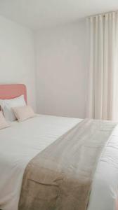 a bedroom with a large white bed with a window at Apolo71 Alojamentos in Bragança