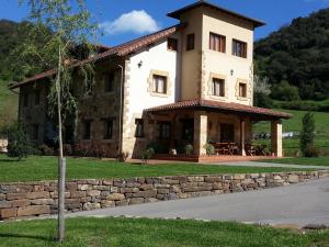 a large house with a stone wall in front of it at Posada El Hoyal in Pesaguero-La Parte